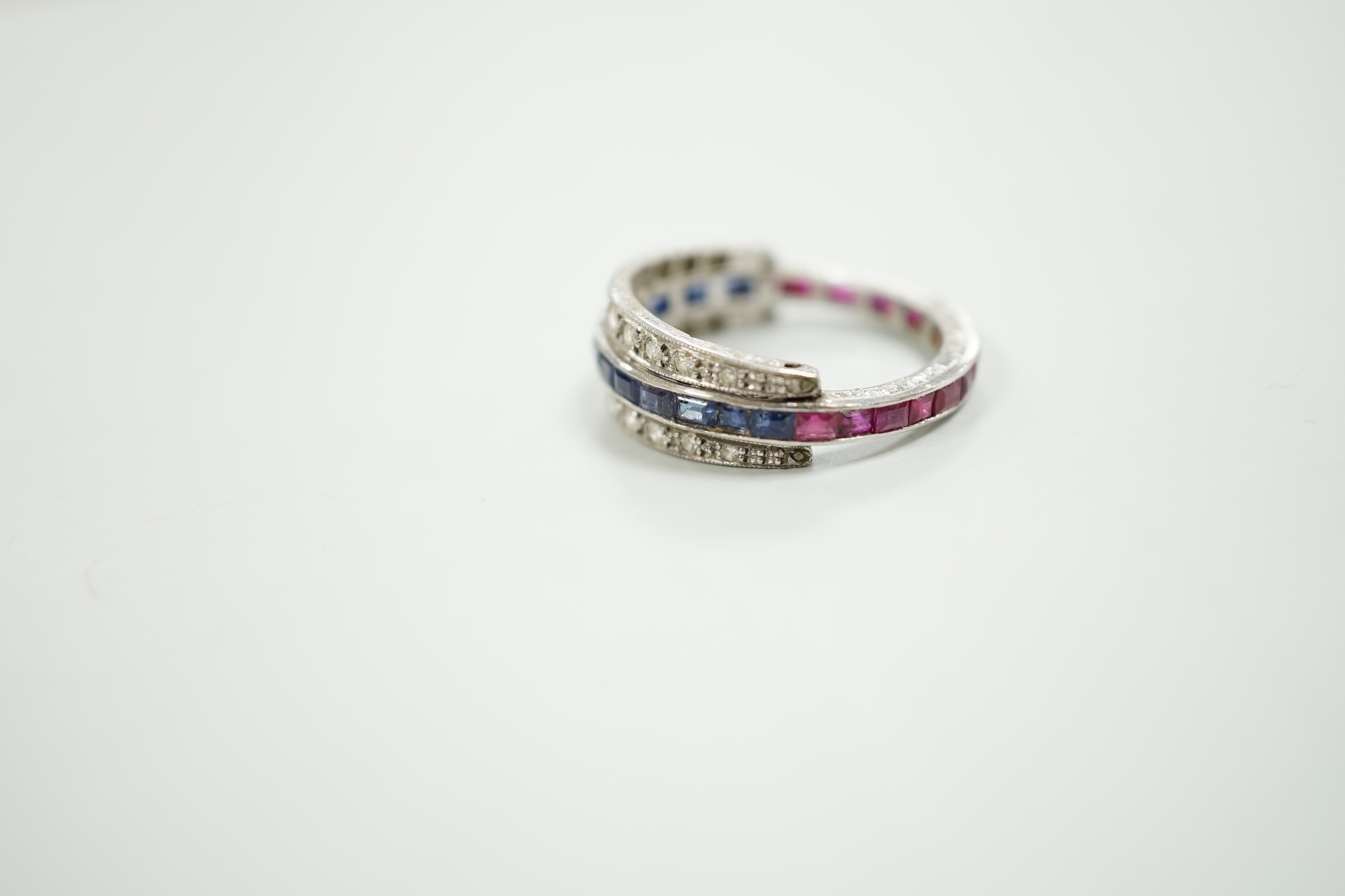 An early to mid 20th century platinum?, ruby, sapphire and diamond set swivelling triple band half eternity ring, size Q, gross weight 4.6 grams.